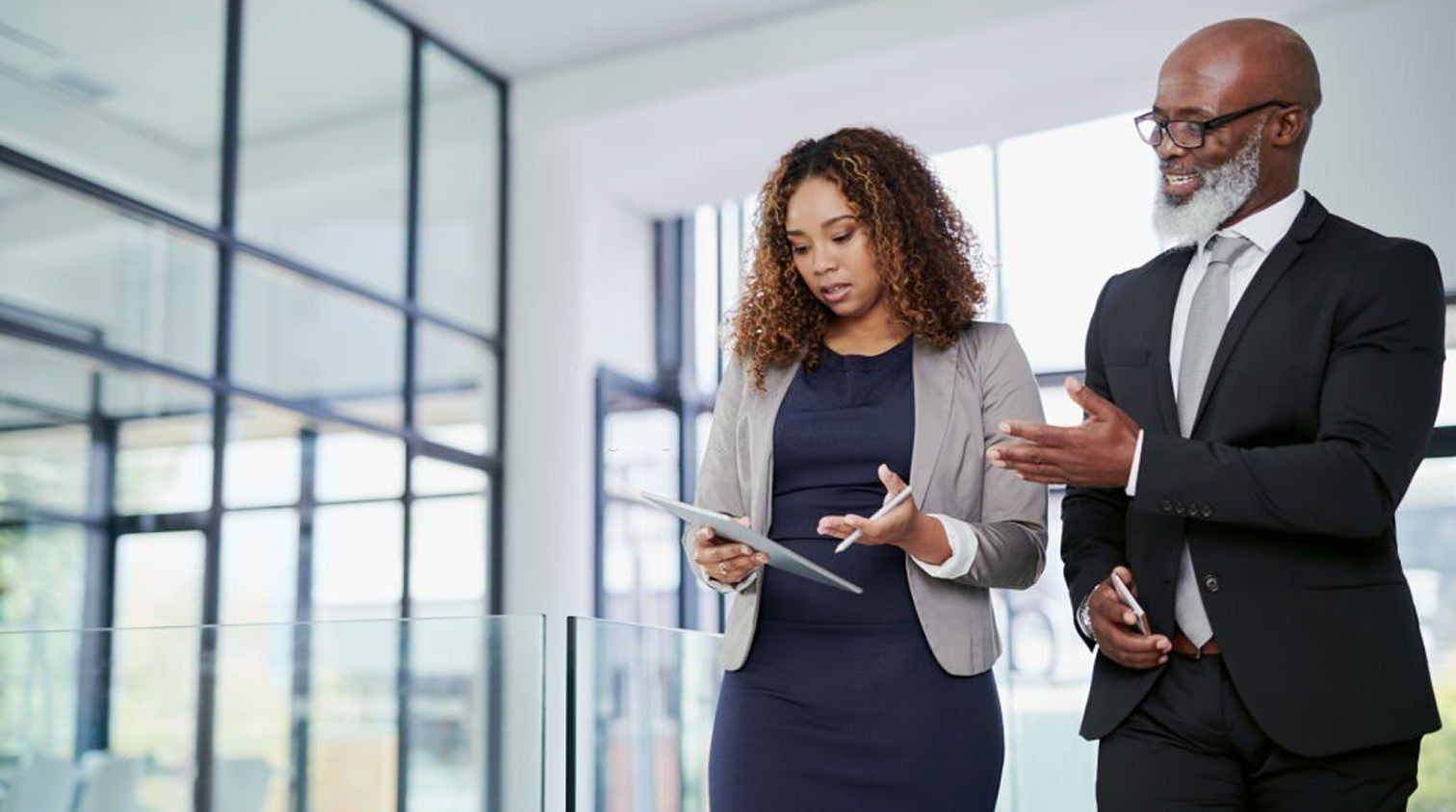 Two professionals collaborating over a tablet in a modern office